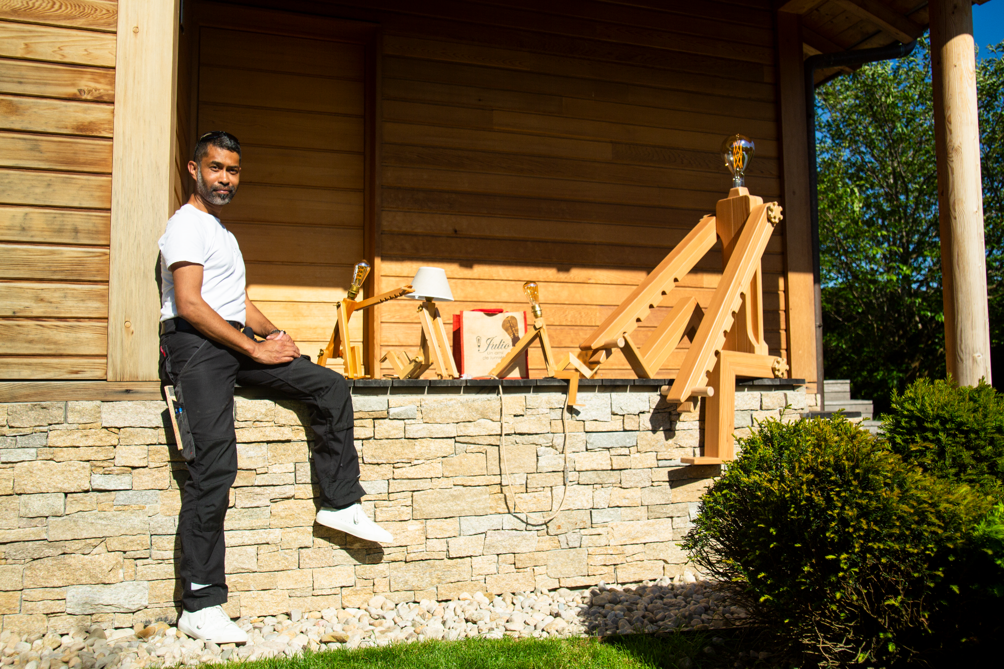 Andry Gisel, artiste menuisier, avec ses créations Julio devant un ouvrage en bois